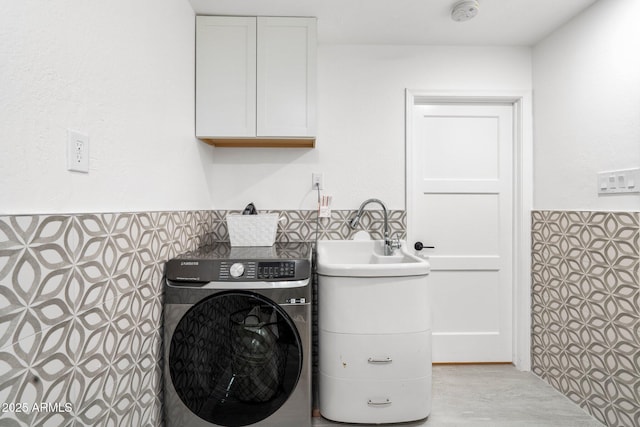 laundry room with cabinet space, a wainscoted wall, washer / dryer, and tile walls