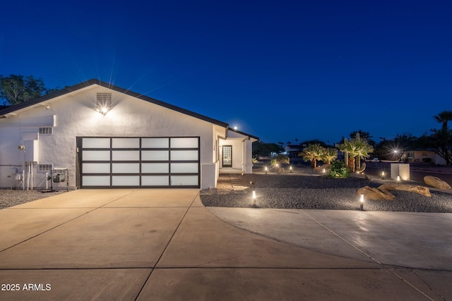 view of front of property with an attached garage, driveway, and stucco siding