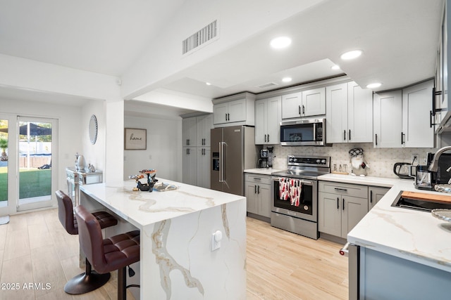 kitchen with visible vents, a sink, appliances with stainless steel finishes, and gray cabinetry
