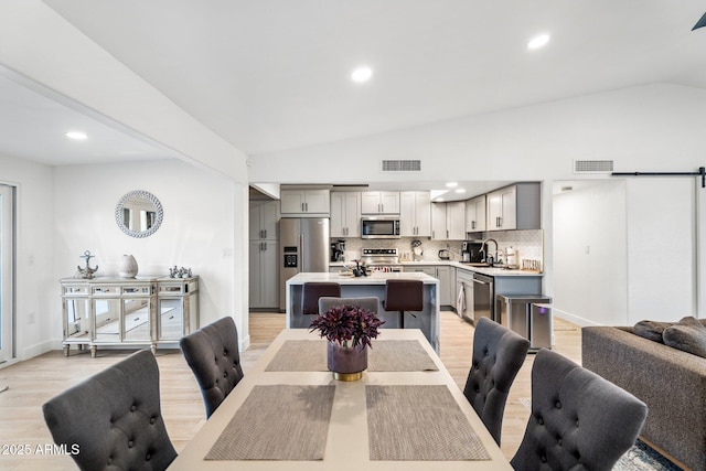 dining space featuring visible vents, light wood-style floors, and lofted ceiling