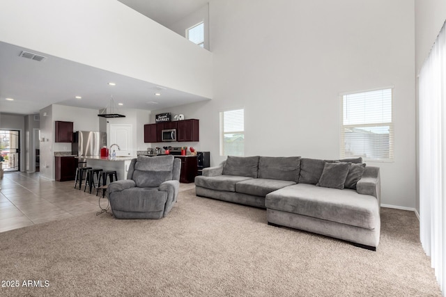 living area with visible vents, light carpet, recessed lighting, light tile patterned flooring, and a towering ceiling