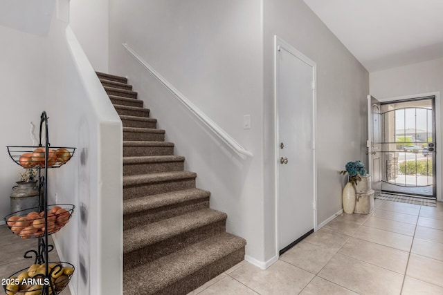 stairway with tile patterned floors and baseboards