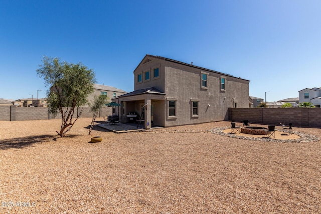 back of house with stucco siding, a patio, a fire pit, and a fenced backyard