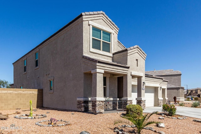 view of front facade with stucco siding, concrete driveway, and fence