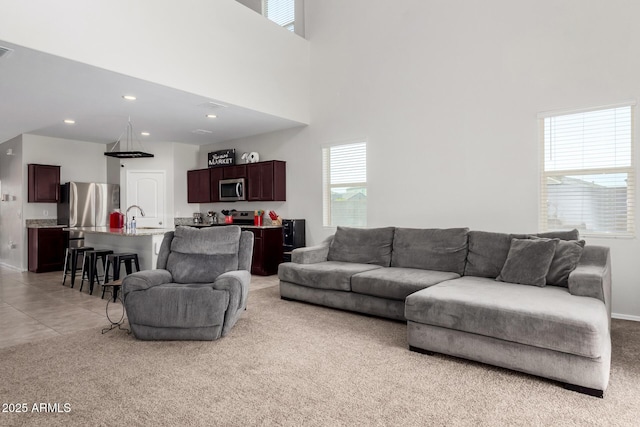 living room featuring recessed lighting, light colored carpet, visible vents, and a towering ceiling