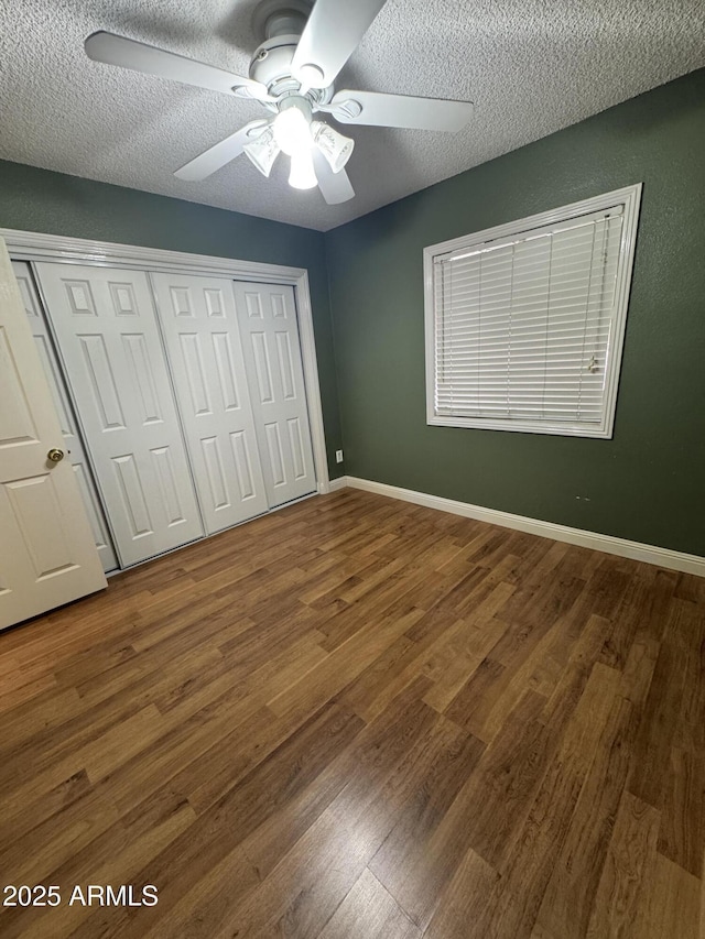 11221 N 91st Dr, Peoria, AZ 85345 - unfurnished bedroom featuring wood finished floors, a closet, a textured ceiling, a ceiling fan, and baseboards