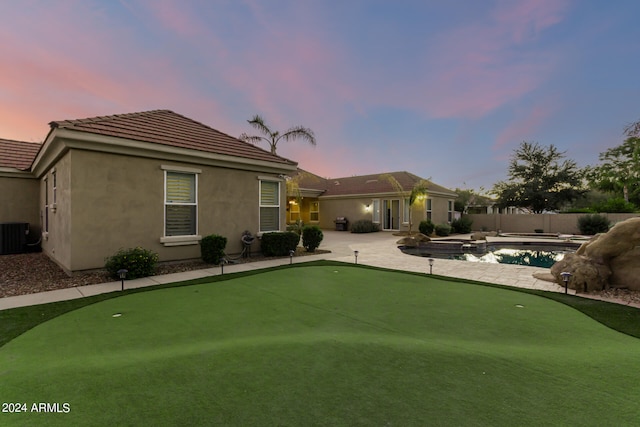 back house at dusk with a fenced in pool, a patio, and cooling unit