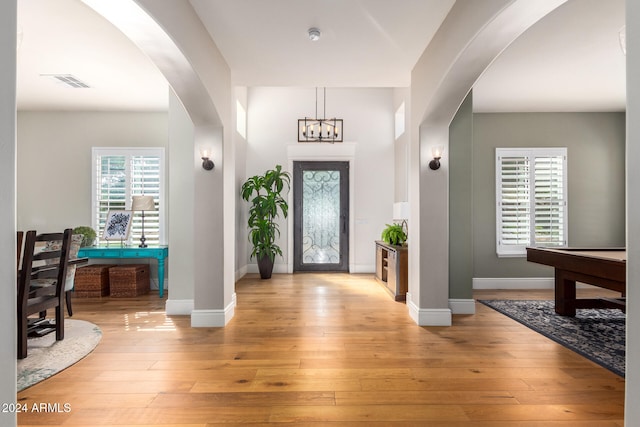 foyer entrance with an inviting chandelier, billiards, and light hardwood / wood-style floors