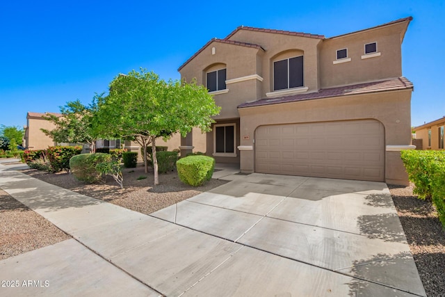 mediterranean / spanish house with a tiled roof, an attached garage, driveway, and stucco siding