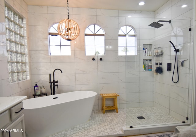 bathroom featuring separate shower and tub, vanity, tile walls, and a notable chandelier