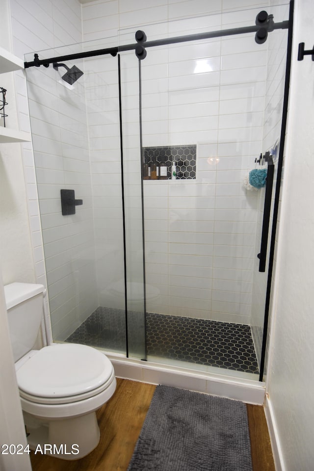 bathroom with wood-type flooring, toilet, and walk in shower