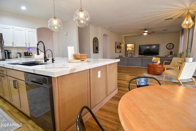 kitchen with tasteful backsplash, sink, a center island with sink, black dishwasher, and light hardwood / wood-style floors