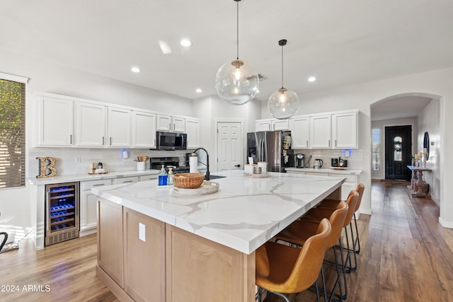 2811 E Riviera Pl, Chandler, AZ 85249 - kitchen featuring beverage cooler, appliances with stainless steel finishes, arched walkways, decorative backsplash, and light wood-style flooring