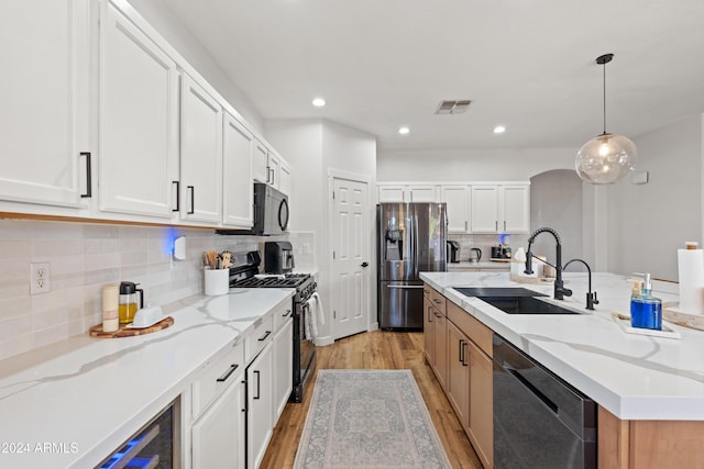 2811 E Riviera Pl, Chandler, AZ 85249 - kitchen with stainless steel appliances, a sink, light wood-style floors, a kitchen island with sink, and white cabinets