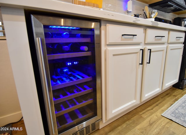 room details featuring light hardwood / wood-style floors, wine cooler, and white cabinetry