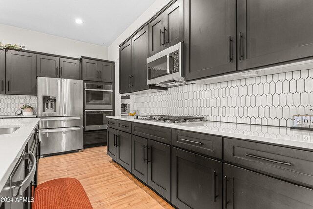 kitchen with decorative backsplash, stainless steel appliances, light hardwood / wood-style floors, and sink