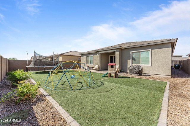 rear view of house with a playground, a trampoline, and a yard