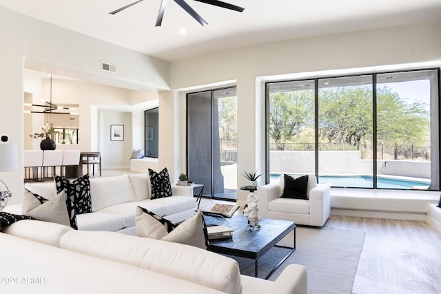 living room with light wood-style flooring, visible vents, recessed lighting, and ceiling fan with notable chandelier
