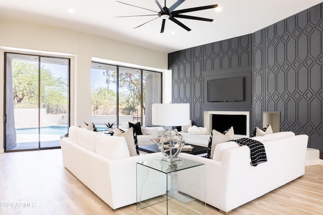 living area with light wood-style flooring, wallpapered walls, an accent wall, and recessed lighting