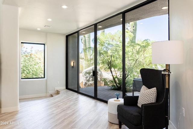 living area with visible vents, a wall of windows, baseboards, wood finished floors, and recessed lighting