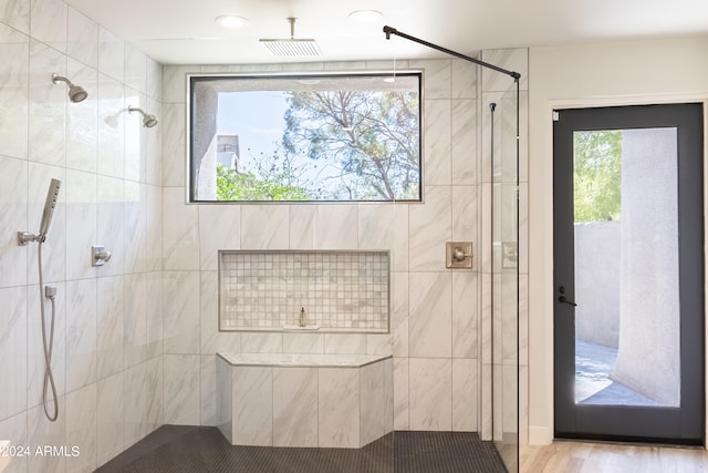 bathroom featuring a wealth of natural light, hardwood / wood-style floors, and tiled shower