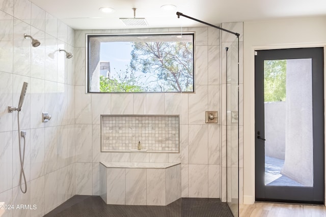 full bath featuring visible vents, tiled shower, and wood finished floors