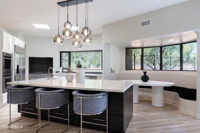 kitchen with plenty of natural light, light stone countertops, hanging light fixtures, and light hardwood / wood-style floors