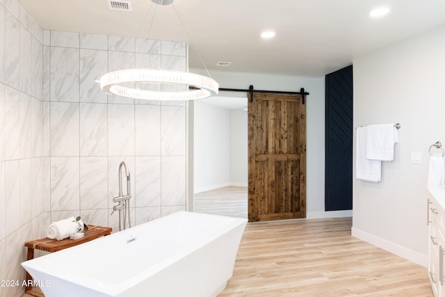 bathroom with tile walls, a tub to relax in, wood-type flooring, and vanity