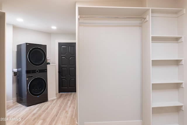 laundry room with recessed lighting, wood finished floors, stacked washing maching and dryer, and laundry area