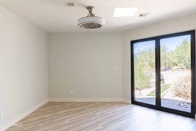 empty room featuring a wealth of natural light, visible vents, and light wood-type flooring