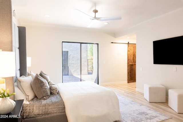 bedroom with a barn door, ceiling fan, light wood-type flooring, and access to exterior