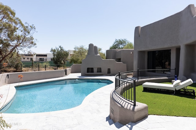 view of swimming pool with a patio, fence, a fenced in pool, and an outdoor fireplace