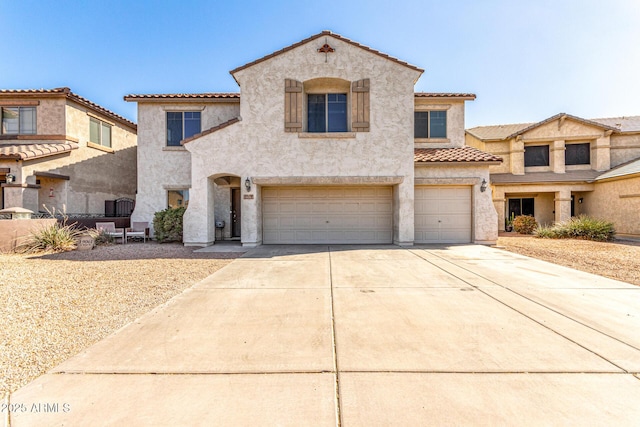 mediterranean / spanish-style house with driveway, a tiled roof, an attached garage, and stucco siding