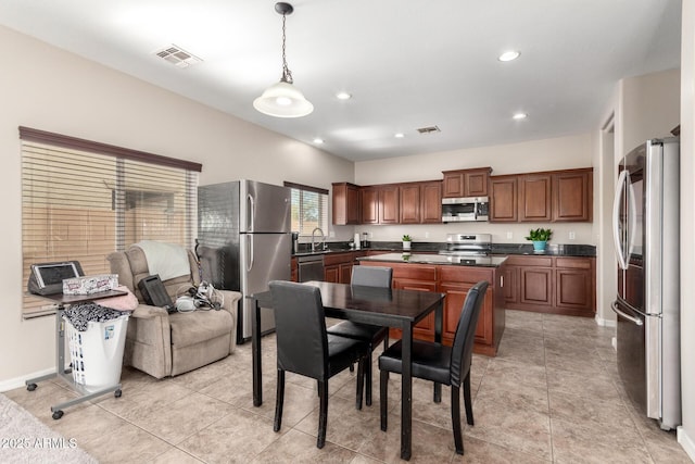 kitchen featuring stainless steel appliances, dark countertops, visible vents, and a sink