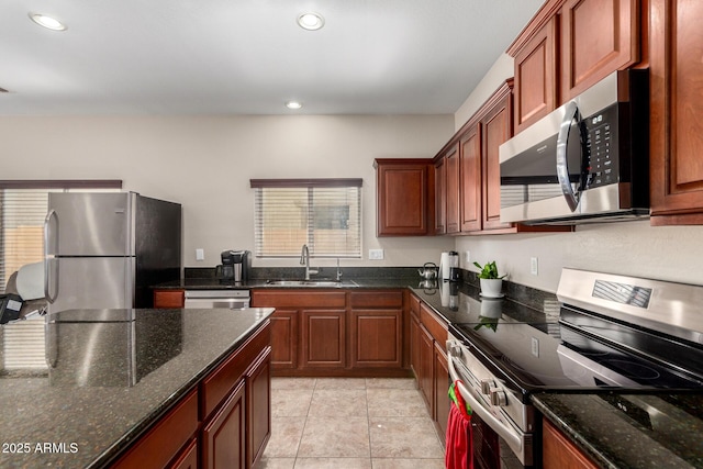 kitchen featuring light tile patterned floors, recessed lighting, stainless steel appliances, a sink, and dark stone countertops