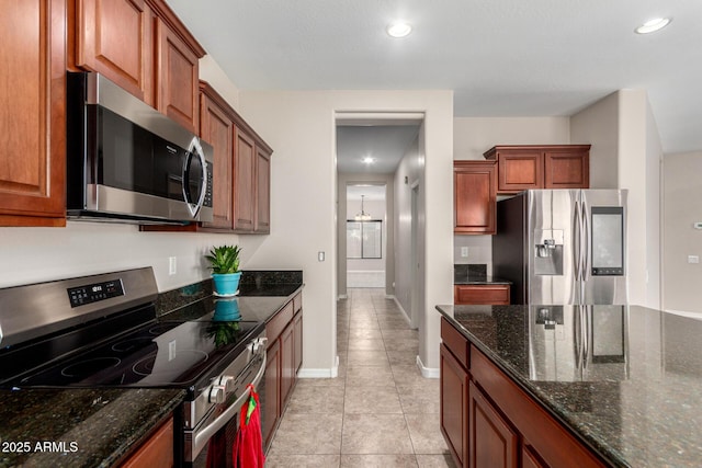 kitchen featuring light tile patterned floors, recessed lighting, stainless steel appliances, baseboards, and dark stone countertops