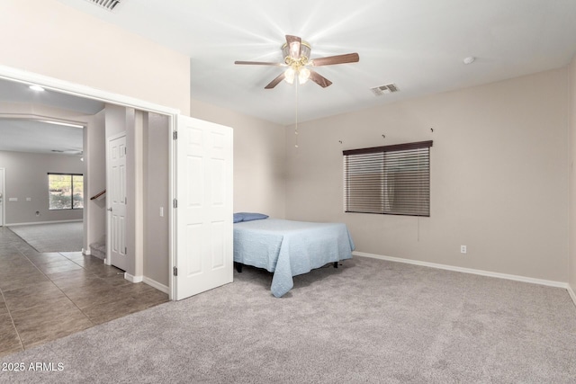 bedroom with carpet floors, a ceiling fan, visible vents, baseboards, and tile patterned floors