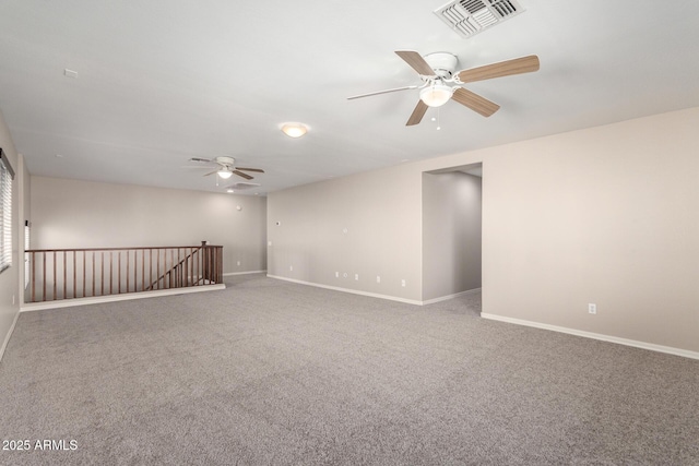 carpeted spare room with visible vents, ceiling fan, and baseboards