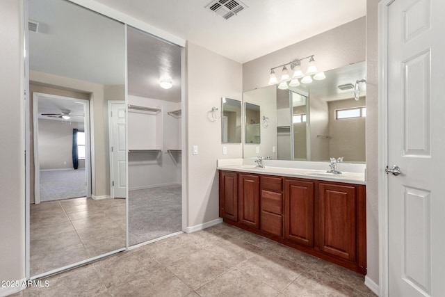 full bath featuring double vanity, baseboards, visible vents, and a sink