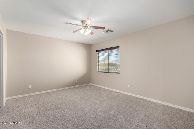 carpeted spare room featuring baseboards, visible vents, and a ceiling fan