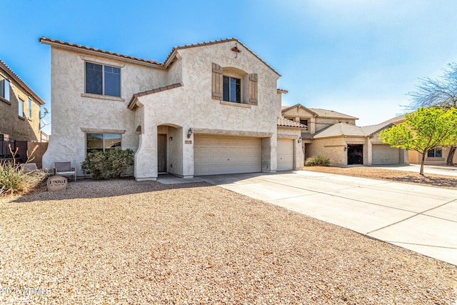 mediterranean / spanish-style house featuring a garage, driveway, a tiled roof, and stucco siding