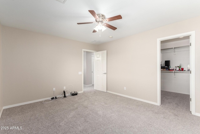 unfurnished bedroom with carpet floors, a closet, a spacious closet, and baseboards