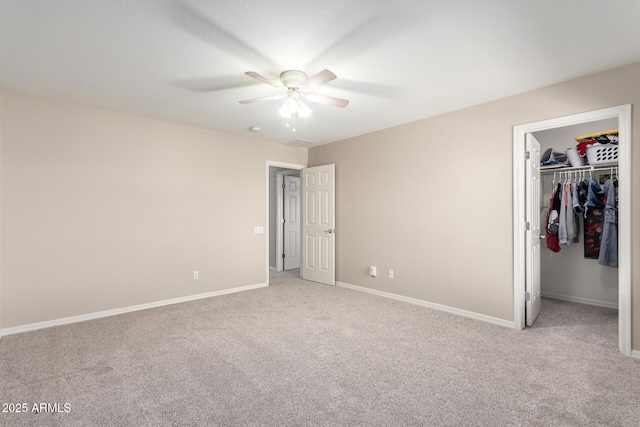 unfurnished bedroom featuring light carpet, a closet, a walk in closet, and baseboards