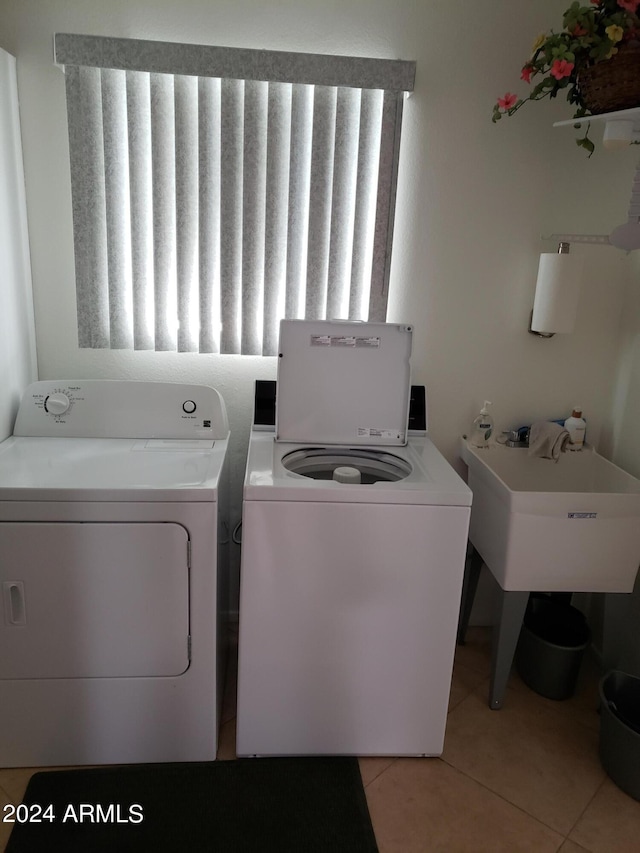 washroom featuring sink, light tile patterned floors, and washer and clothes dryer