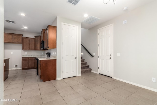 kitchen featuring black appliances, light stone countertops, and light tile patterned floors