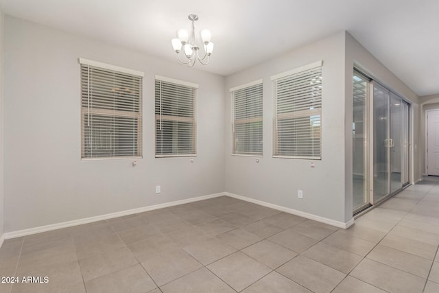 empty room with light tile patterned floors and a notable chandelier