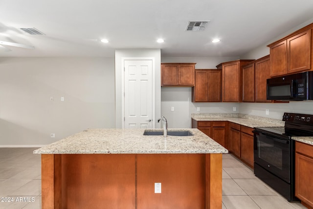 kitchen with light stone countertops, sink, an island with sink, and black appliances