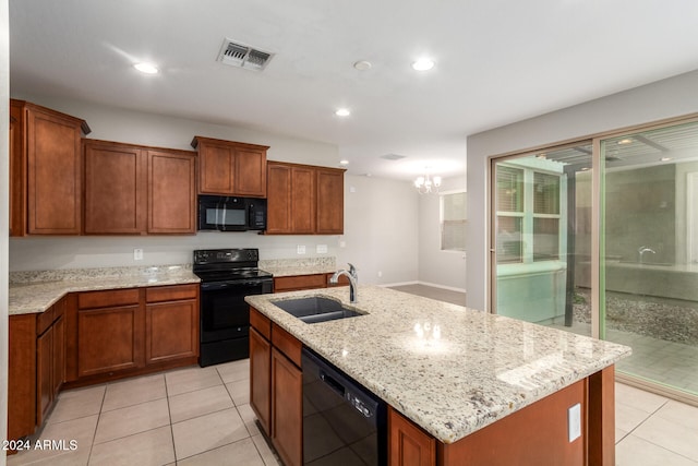 kitchen with light stone countertops, sink, a chandelier, a center island with sink, and black appliances