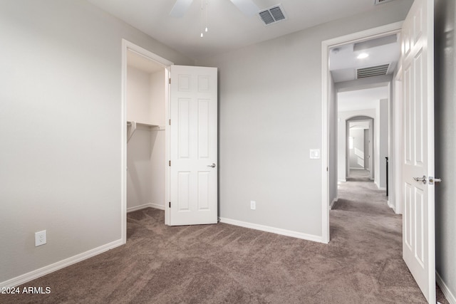 unfurnished bedroom with carpet, ceiling fan, a spacious closet, and a closet