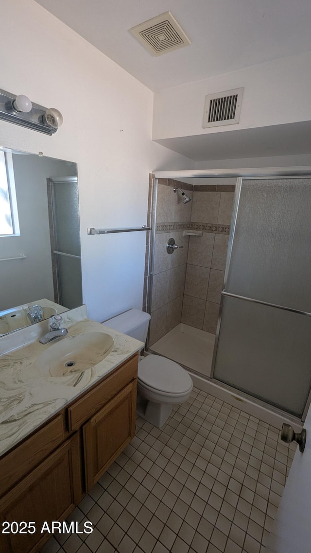 bathroom with vanity, a shower with shower door, tile patterned floors, and toilet